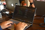 a man using a laptop computer on a wooden table