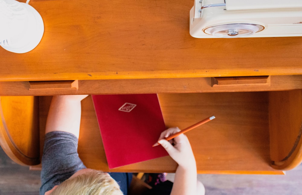 a child is writing on a piece of red paper