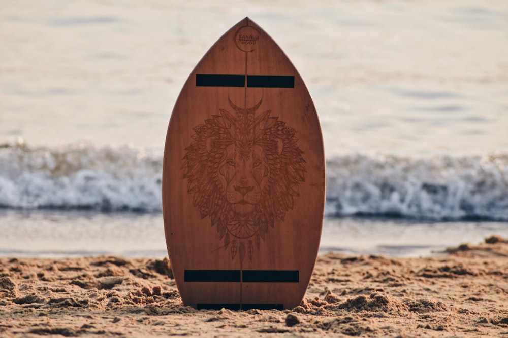 a wooden surfboard sitting on top of a sandy beach