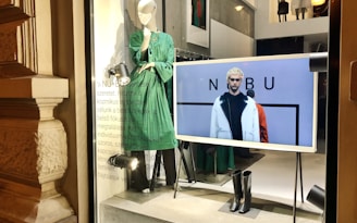 a window display with mannequins dressed in green and black