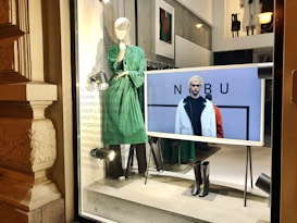 a window display with mannequins dressed in green and black