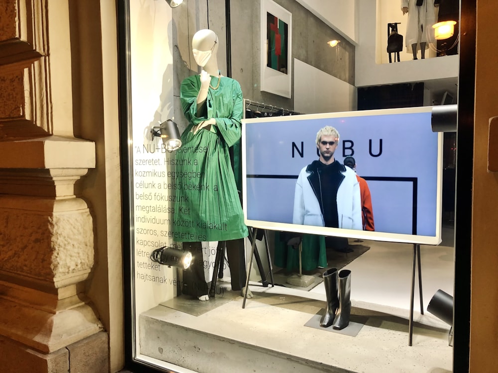 a window display with mannequins dressed in green and black