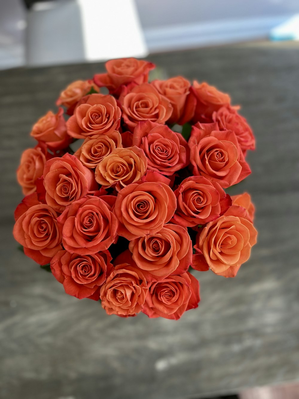 Un ramo de rosas naranjas sentado encima de una mesa
