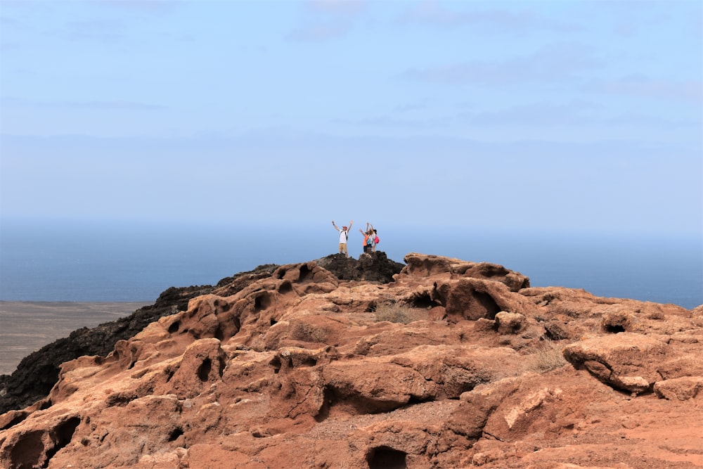 un groupe de personnes debout au sommet d’une colline rocheuse