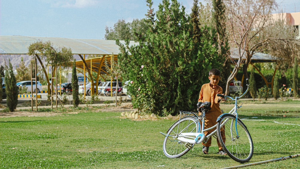 a man standing next to a bike on a lush green field