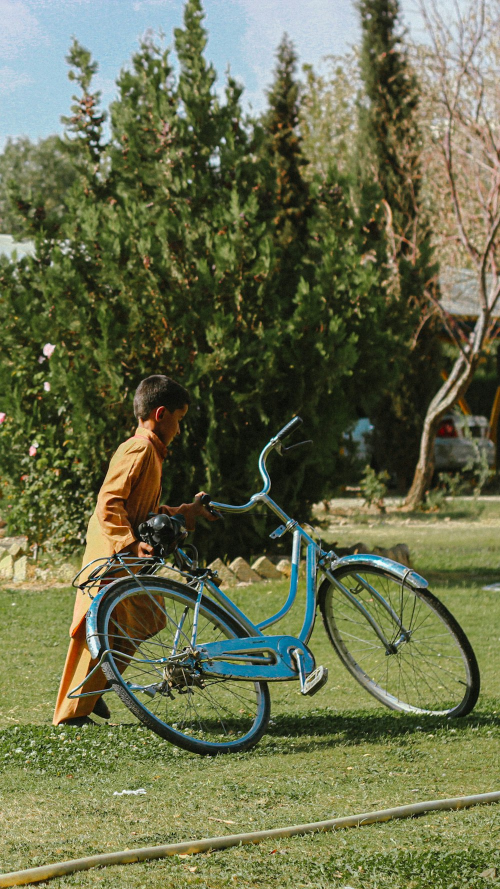 a man sitting on the grass next to a blue bike