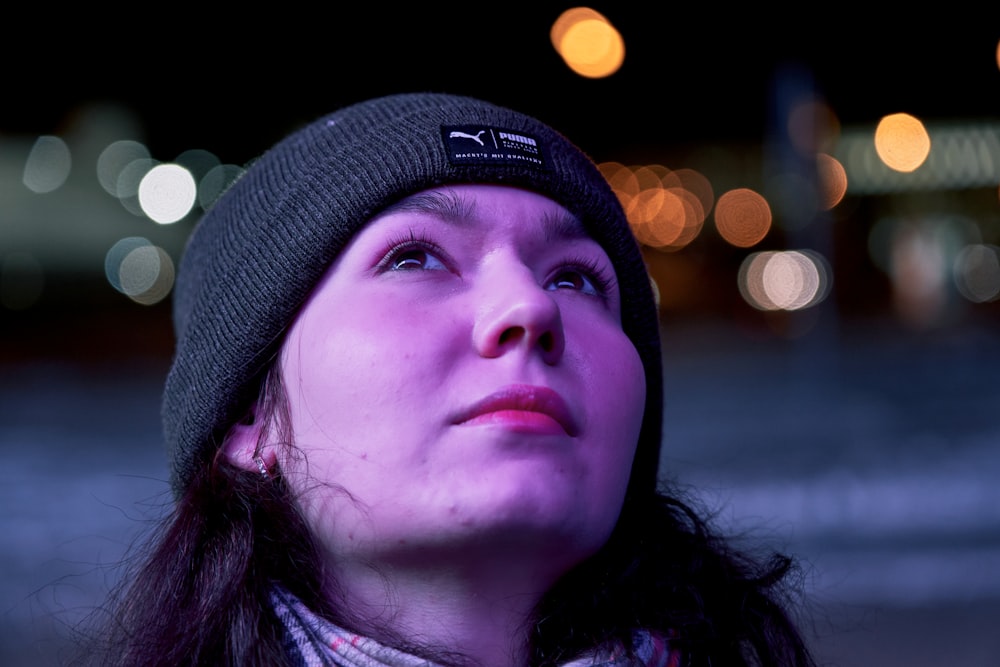 a woman wearing a beanie looking up at the sky