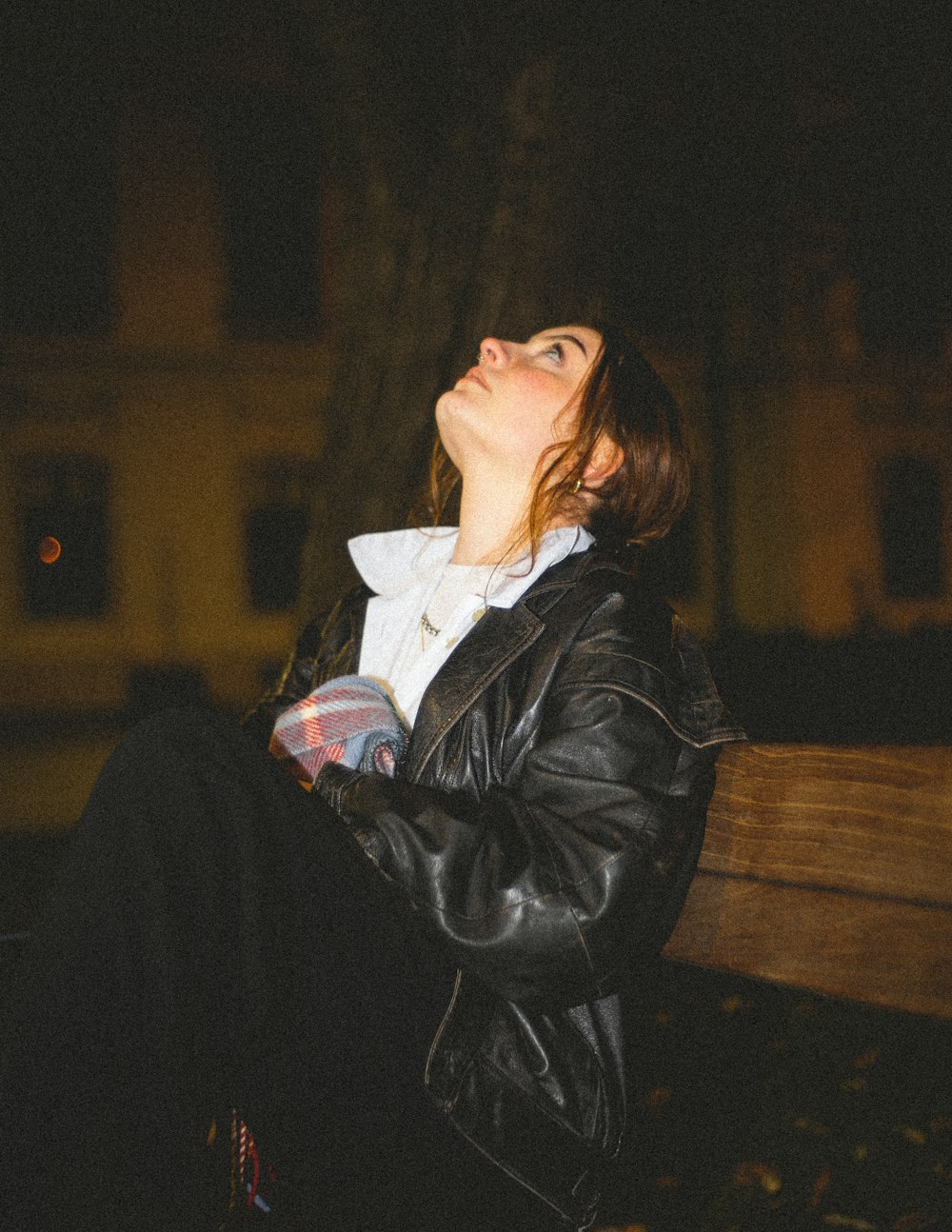 a woman sitting on a bench in the dark