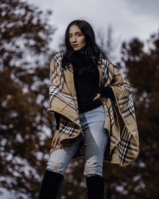 A model wrapped in a charcoal gray wool shawl standing outdoors on a crisp autumn day.