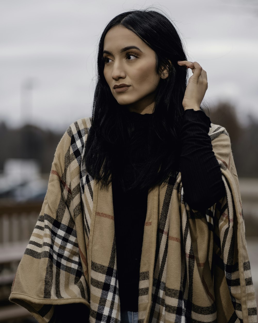 a woman in a black shirt and a plaid coat