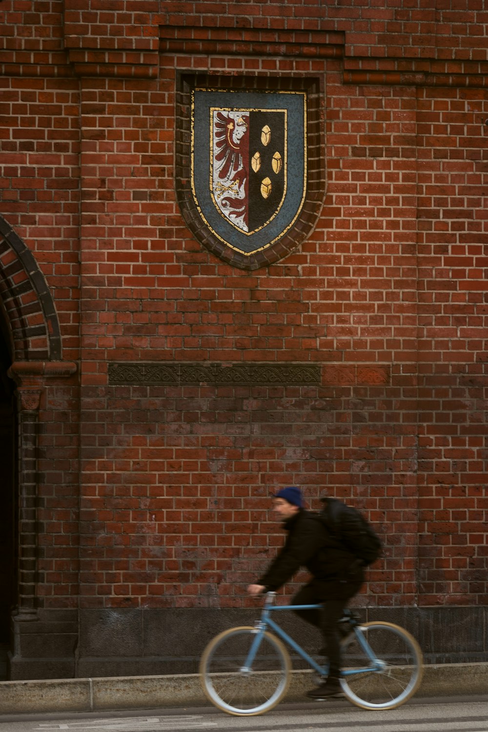 a man riding a bike down a street past a brick building