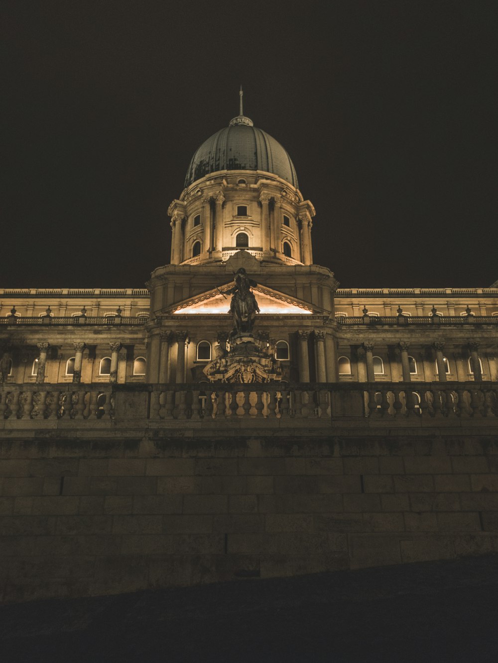 a building lit up at night with a statue in front of it