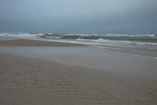 a sandy beach with waves coming in to shore