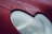 Close-up view of a car's headlight with a red body exterior. The texture on the red paint is rough and resembles a web-like pattern. The headlight appears to have a frosty or matte finish.