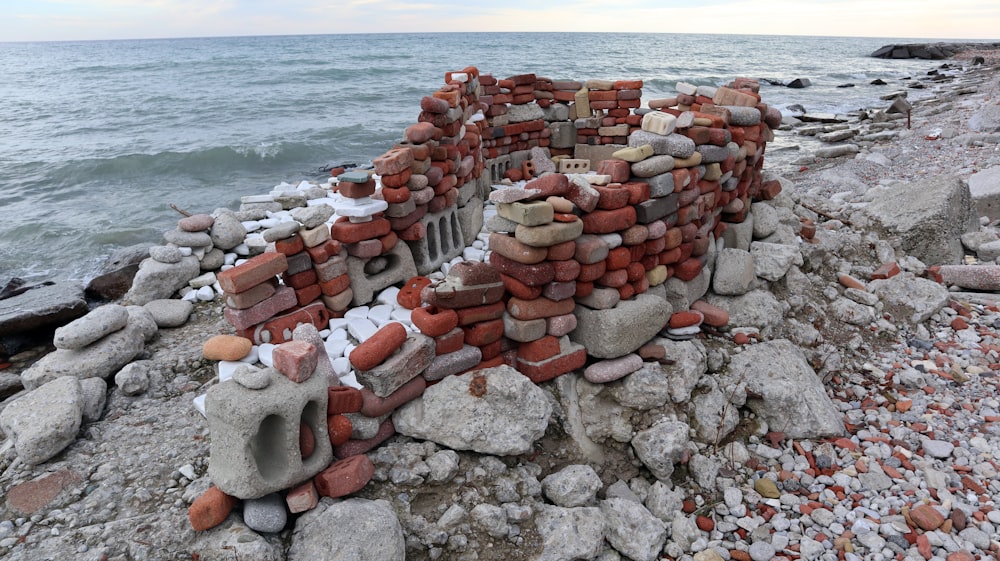 a pile of rocks sitting on top of a beach next to the ocean