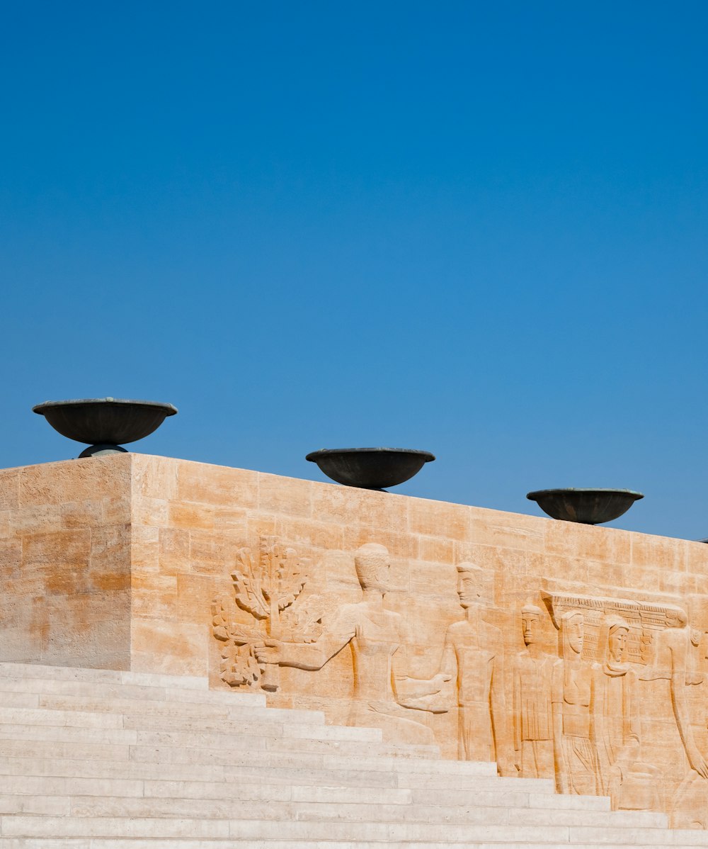 a row of black bowls sitting on top of a stone wall