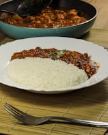 a white plate topped with rice covered in sauce