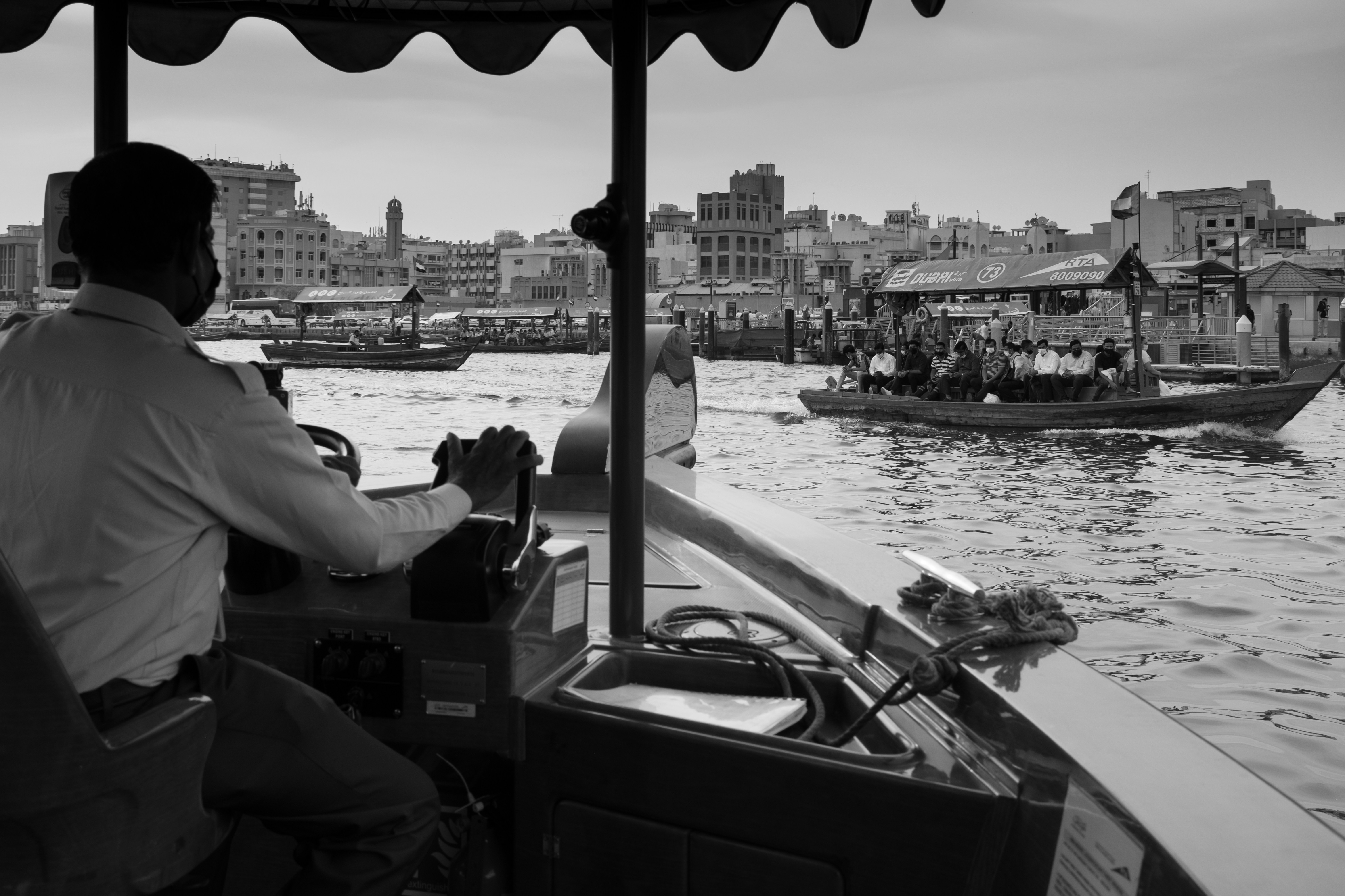 a black and white photo of a man driving a boat