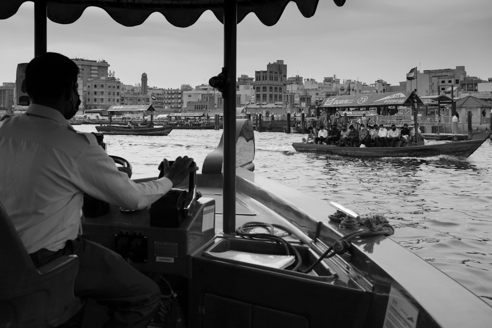 a black and white photo of a man driving a boat