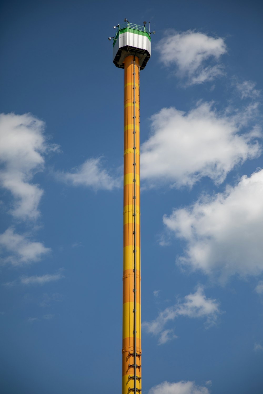 a tall yellow and green tower with a sky background