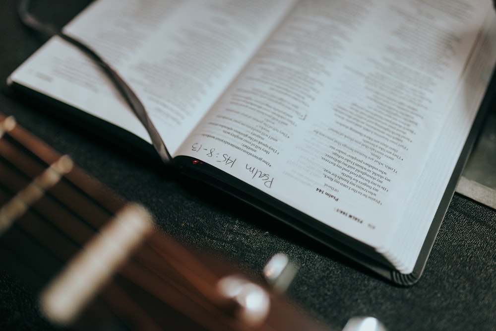 an open book sitting on top of a table next to a guitar