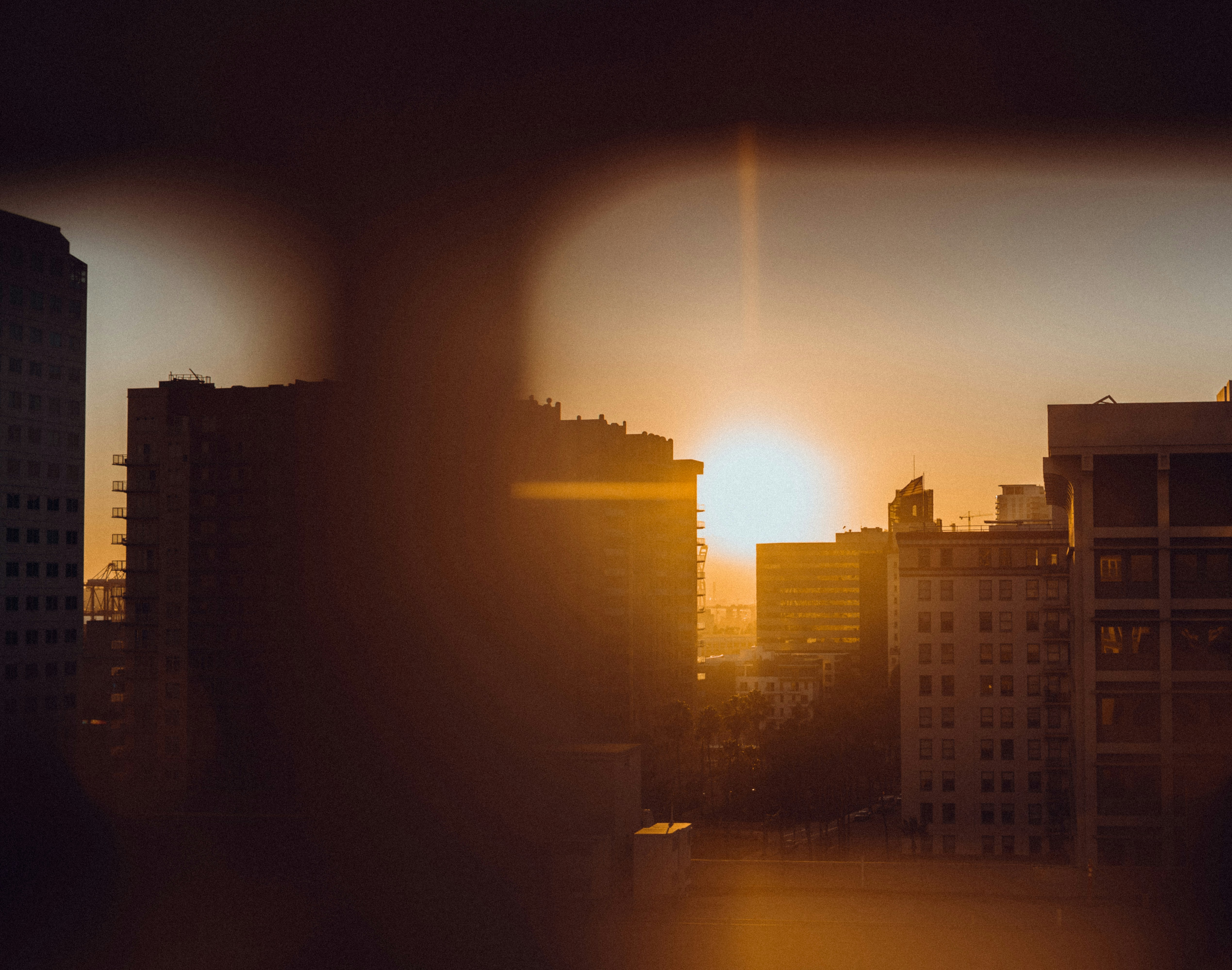 the sun is setting over a city with tall buildings