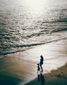 a woman and a child are standing on the beach