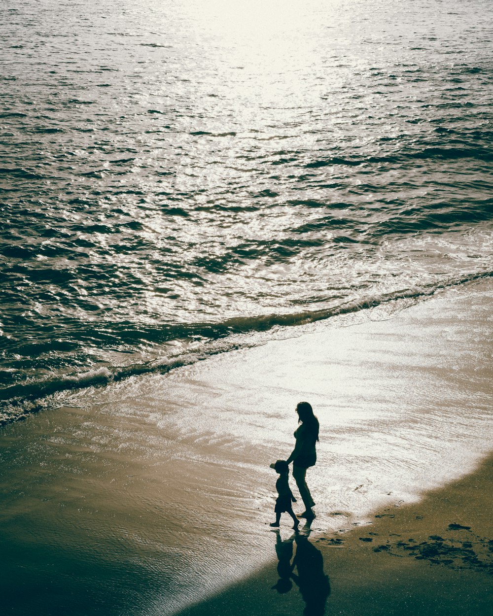 a woman and a child are standing on the beach