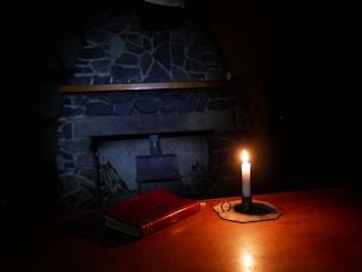 A flickering candle casting warm light inside a rustic cabin filled with old books and Norse symbols.