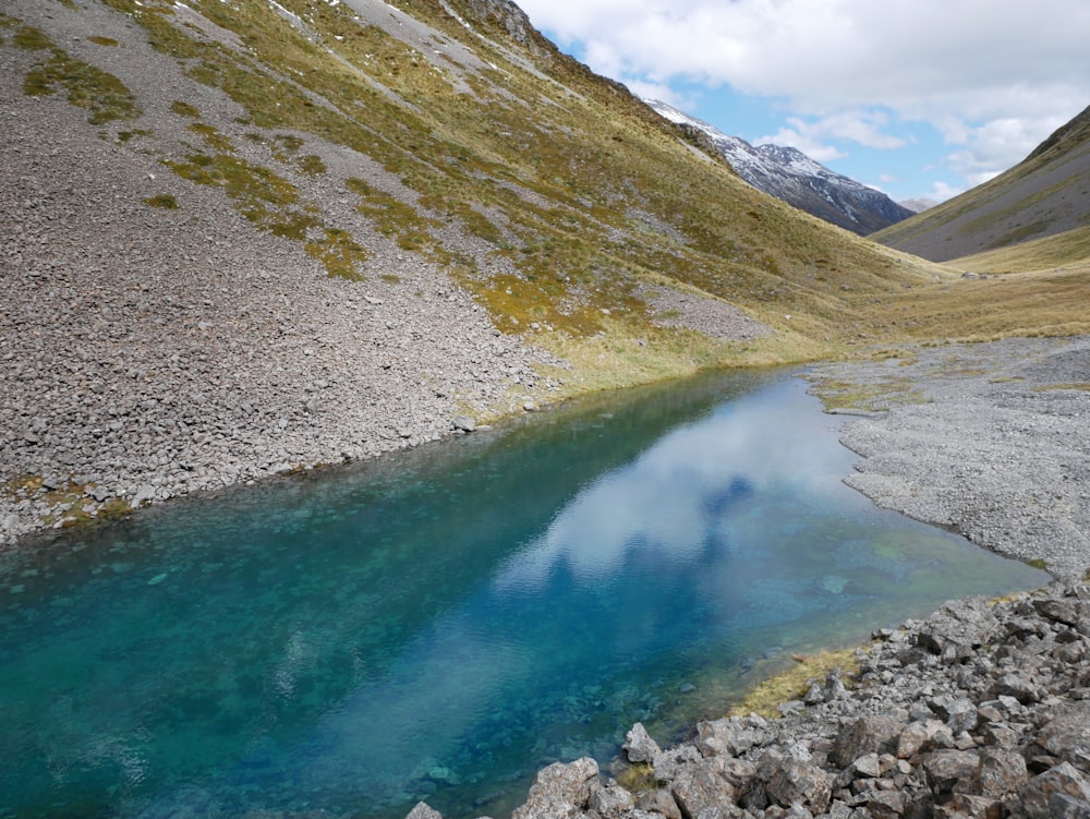 a blue pool of water in the middle of a mountain