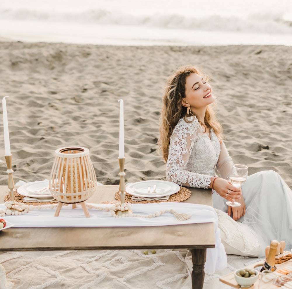 a woman sitting at a table on the beach