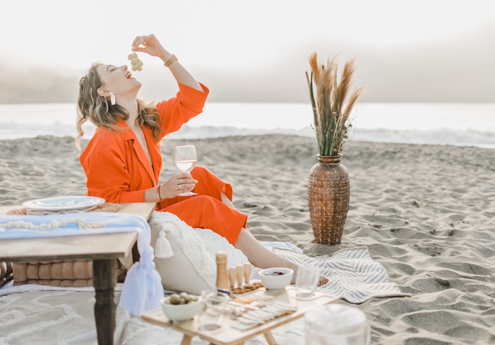 a woman in an orange dress sitting on a beach