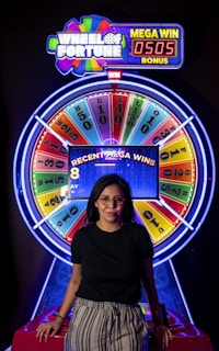 a woman standing in front of a wheel of fortune game