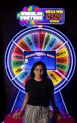 a woman standing in front of a wheel of fortune game