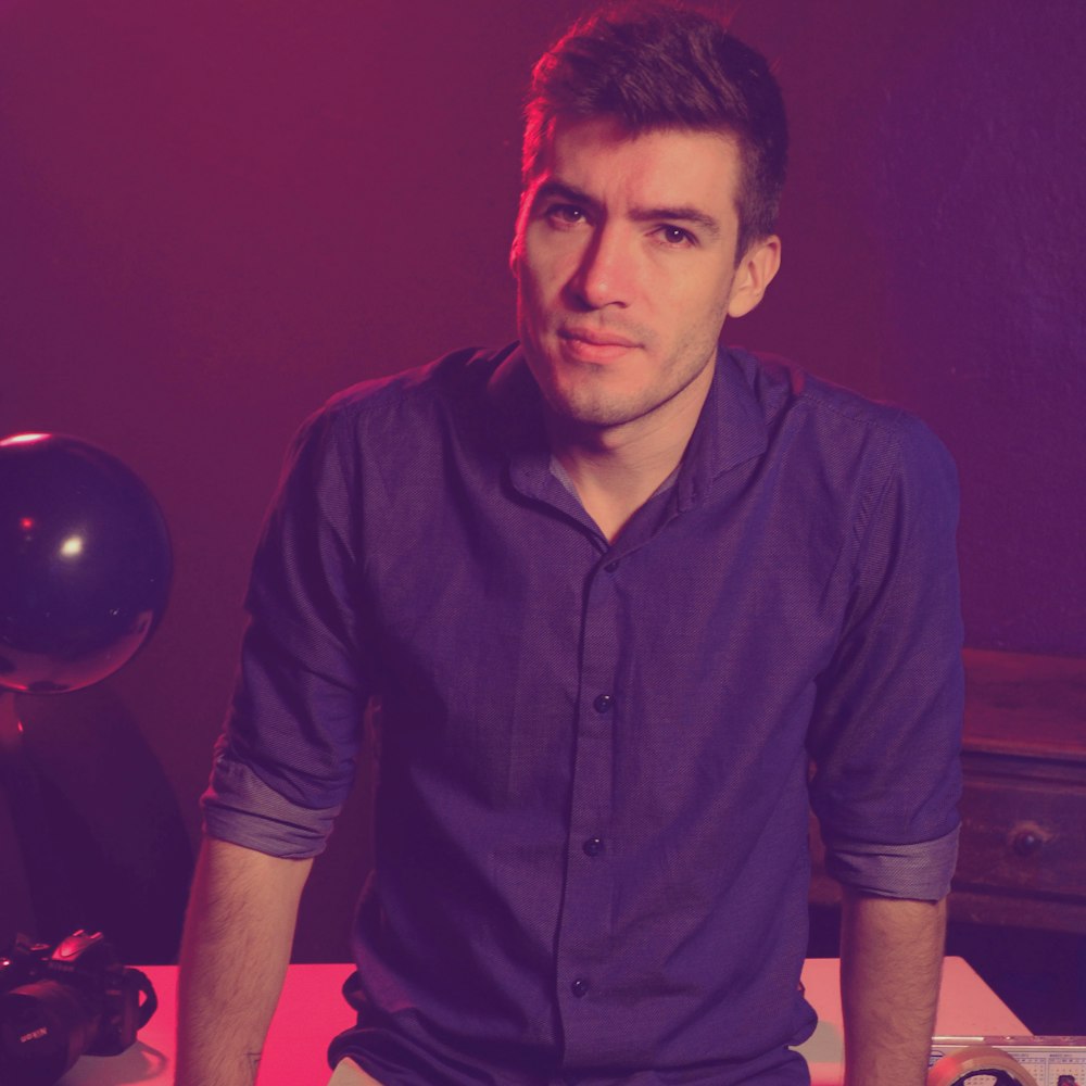 a man in a purple shirt sitting at a table