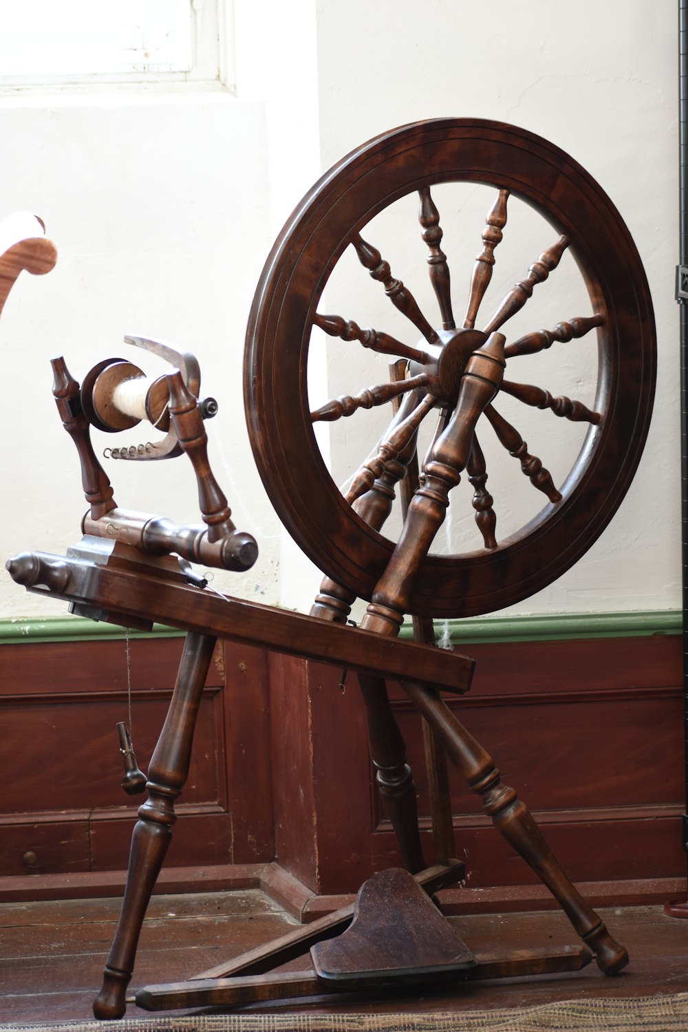 a wooden spinning wheel sitting on top of a wooden stand