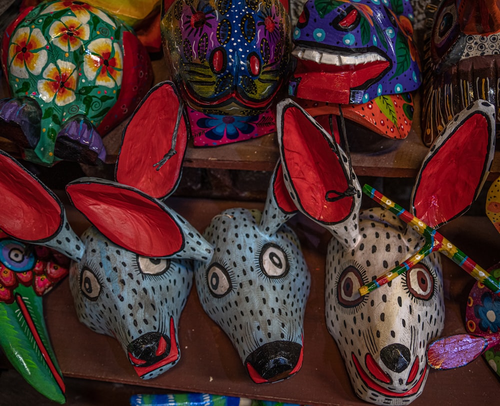a group of colorful masks sitting on top of a shelf