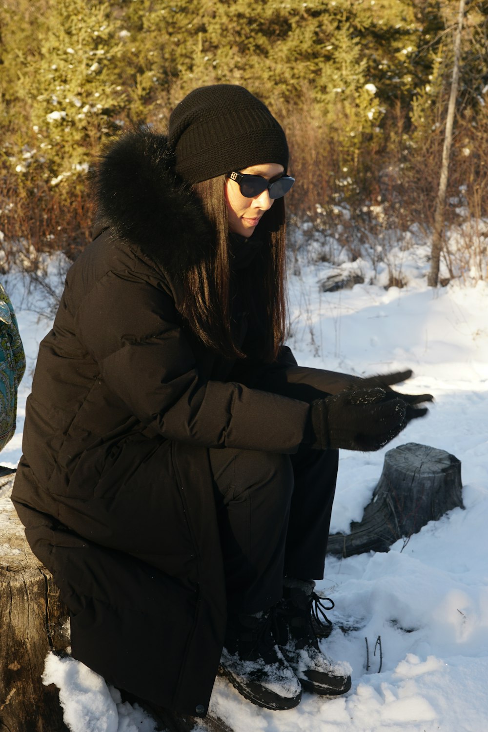 a woman sitting on a log in the snow