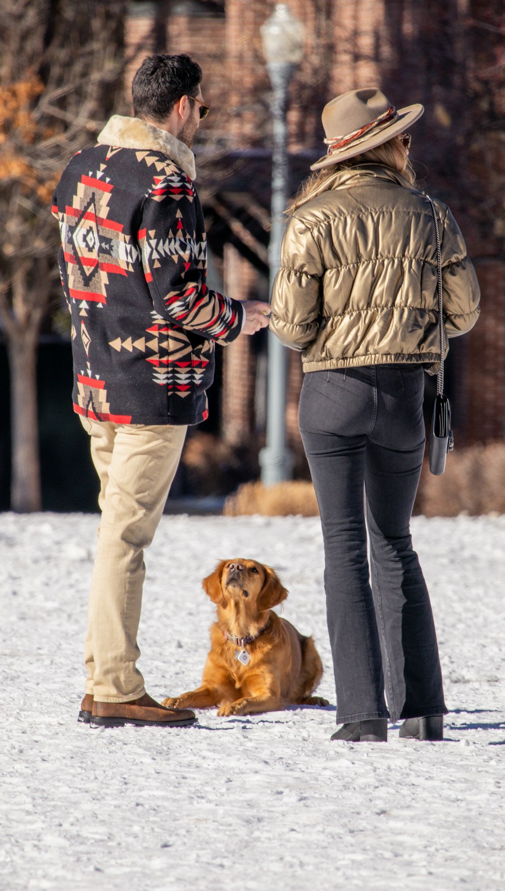 a man and a woman standing next to a brown dog