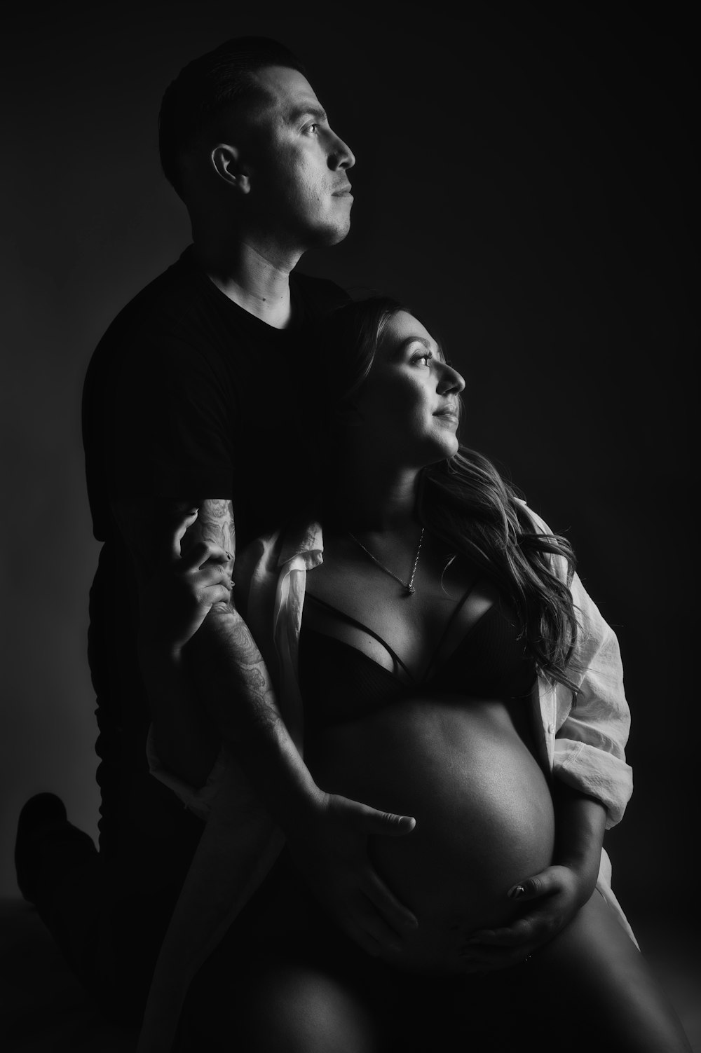 a black and white photo of a pregnant couple