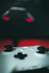 Close-up of a gamer holding a controller with colorful LED lights glowing in a dark room.