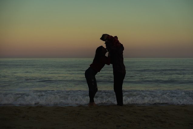 a couple of people standing on top of a sandy beach