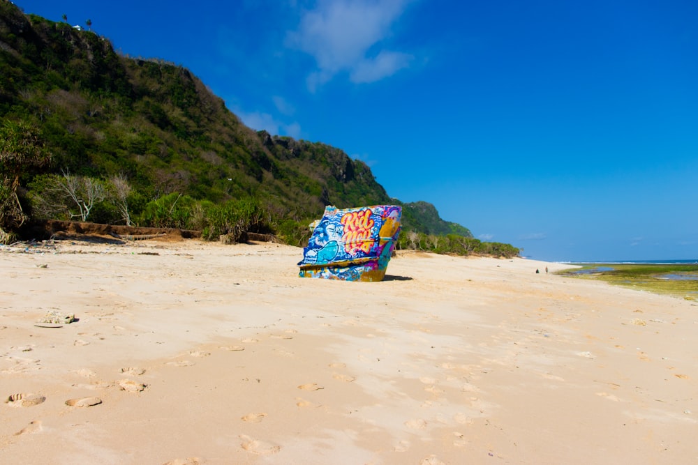 a colorful boat on a sandy beach with a mountain in the background