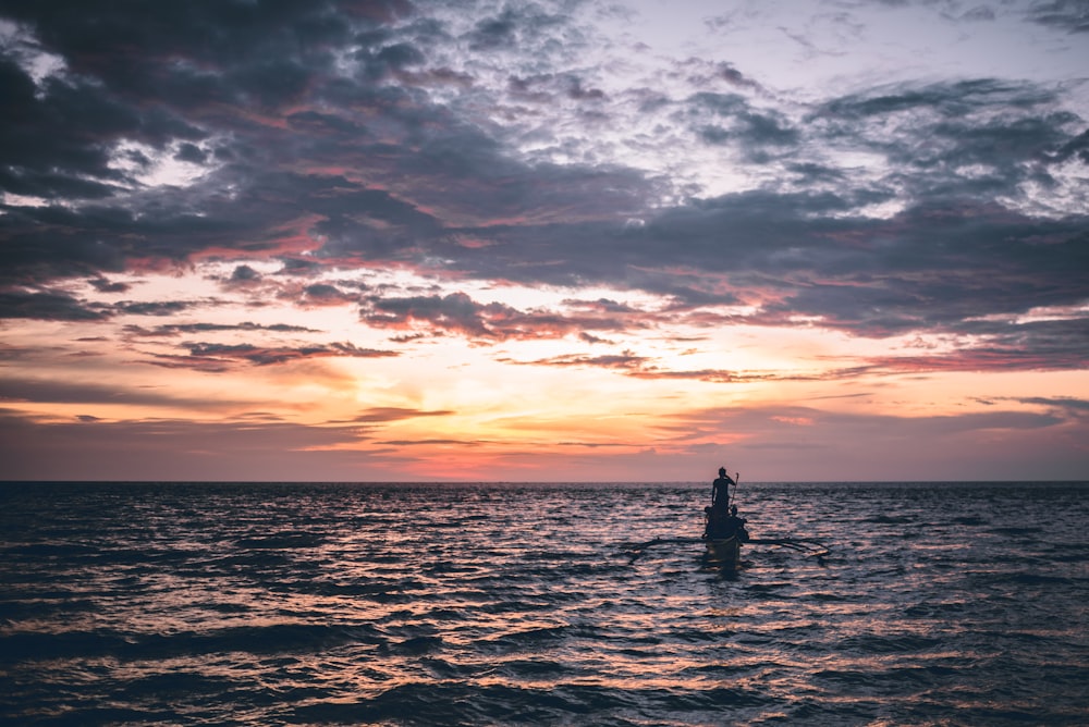 uma pessoa montando uma prancha de surf no oceano ao pôr do sol