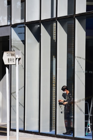 Hands adjusting a large-format printed sign on a storefront window.