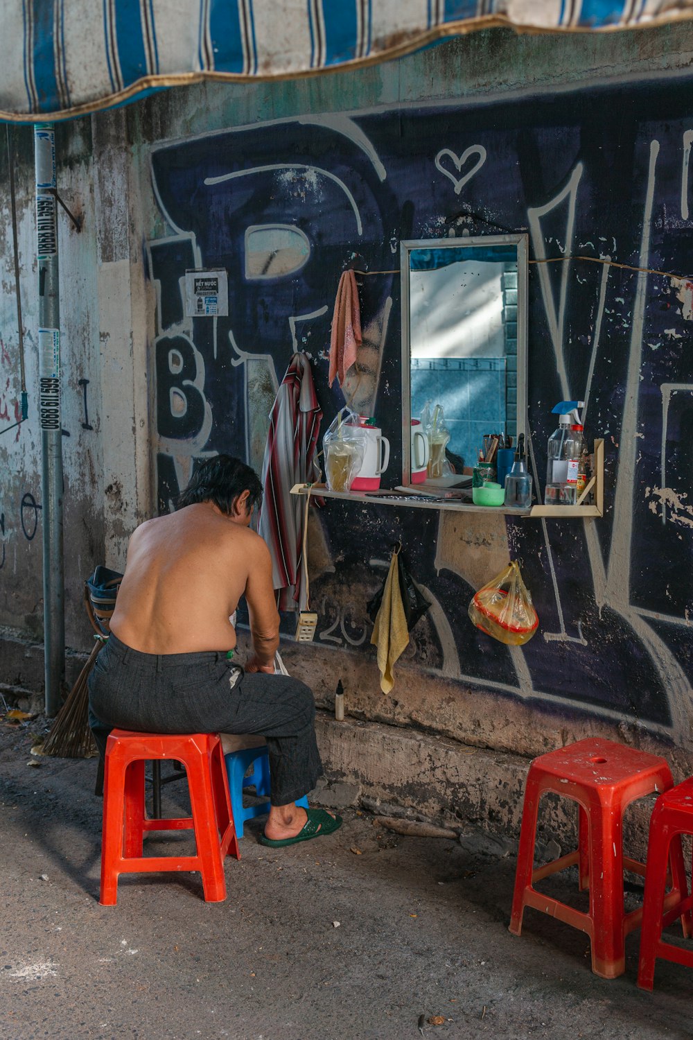 a man sitting on a stool in front of a building