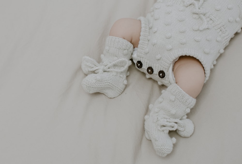 a baby wearing a white knitted outfit and booties