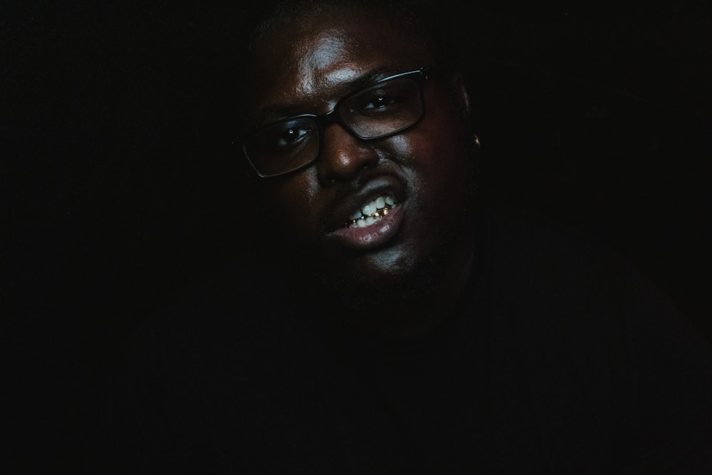 a man with glasses and a dark background