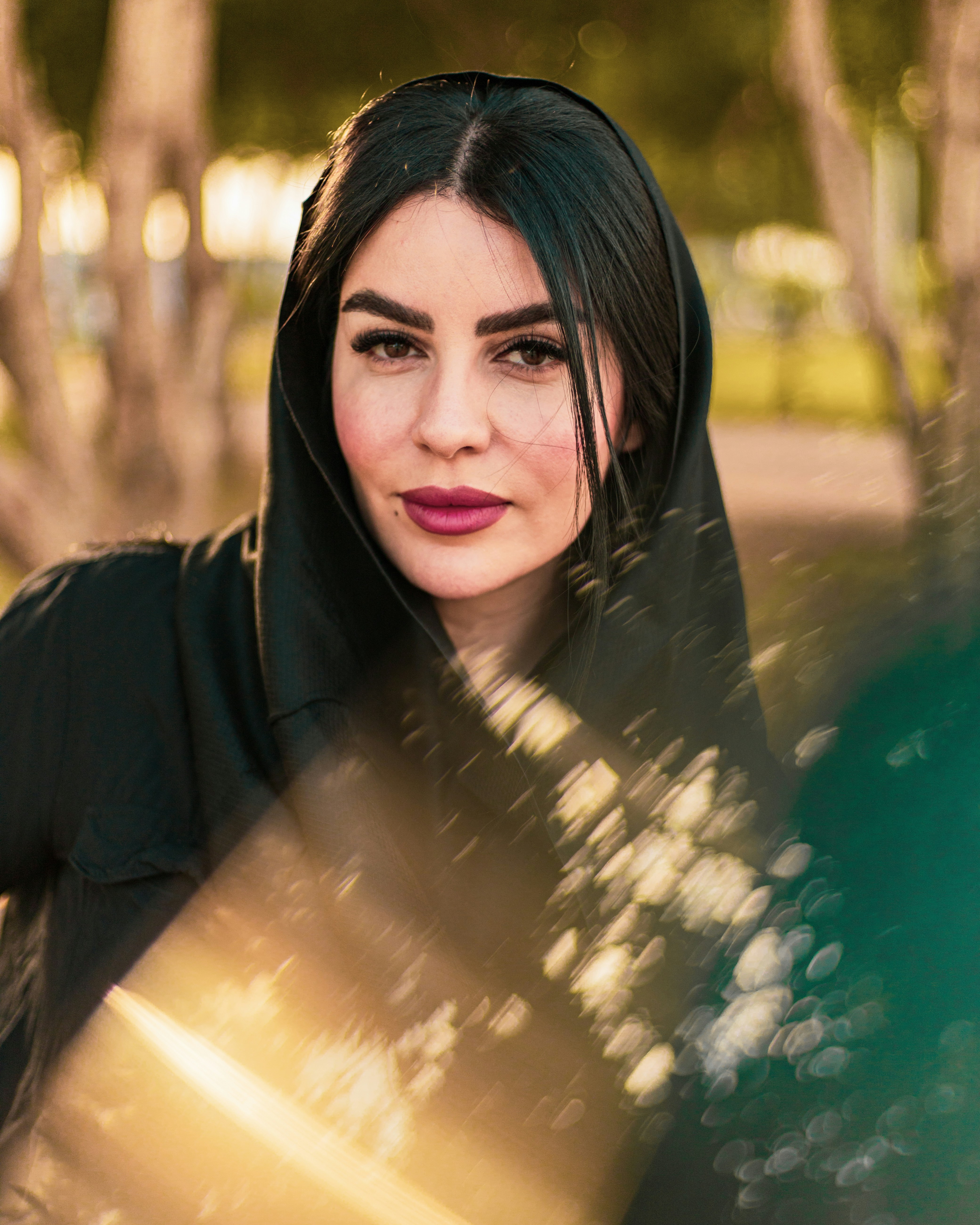 Seorang wanita berhoodie hitam sedang berpose untuk berfoto