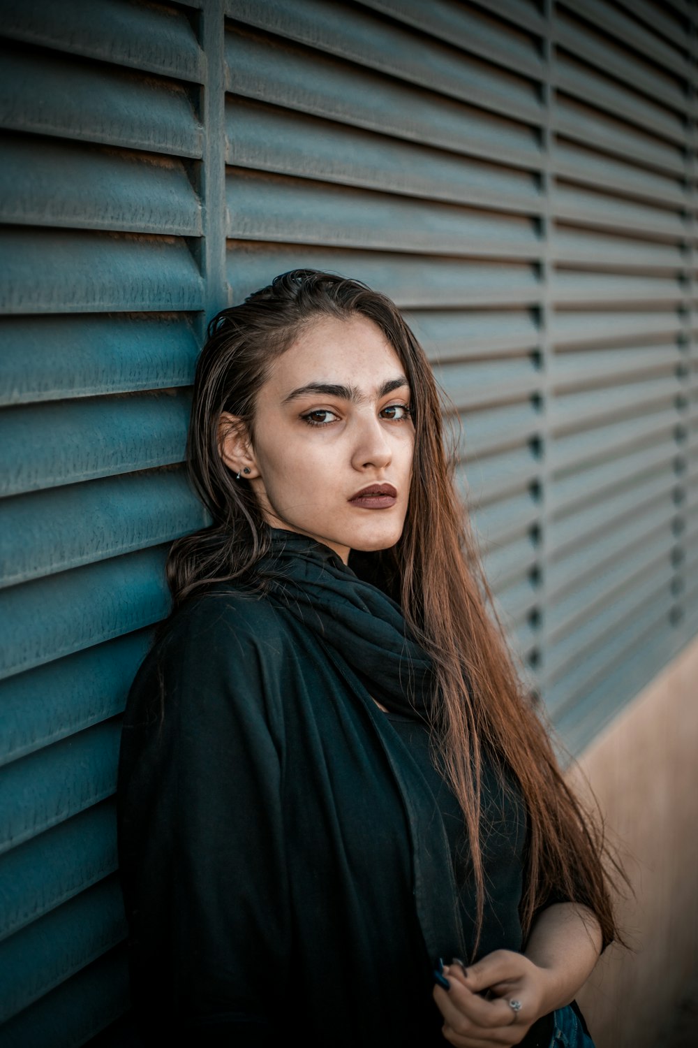 a woman with long hair leaning against a wall